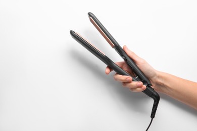 Woman holding corrugated hair iron on white background, closeup