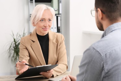 Happy woman with clipboard and man at wooden table in office. Manager conducting job interview with applicant