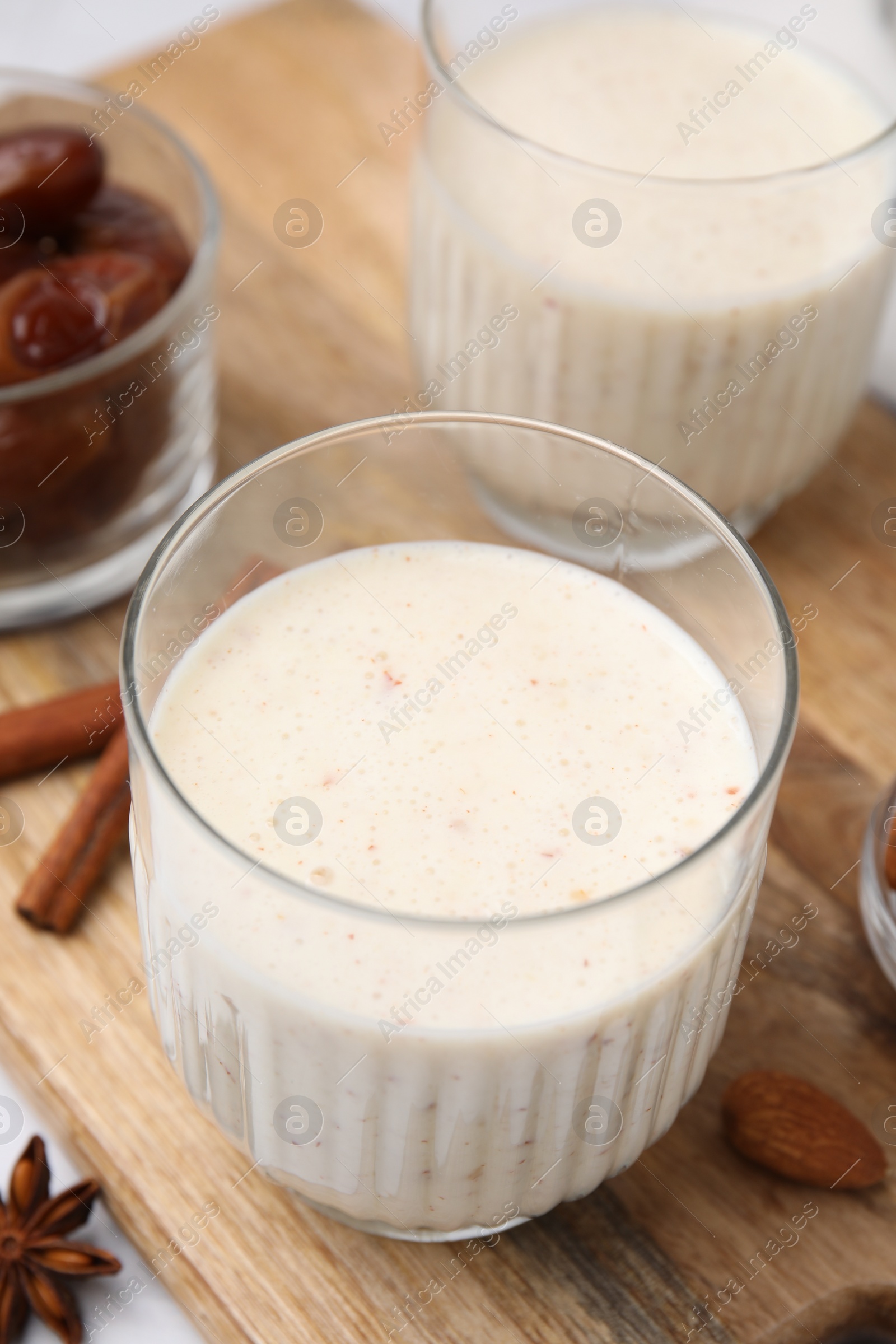 Photo of Glasses of delicious date smoothie on wooden board, closeup