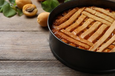Delicious apricot pie in baking dish on wooden table, closeup. Space for text