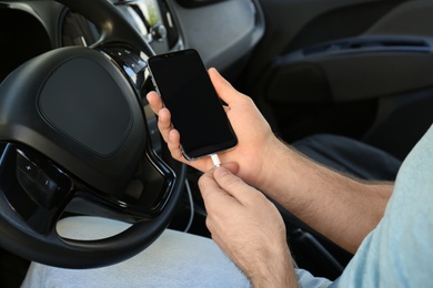 Photo of Man charging phone with USB cable in car