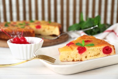 Piece of delicious pineapple pie with cherry and mint on white wooden table, closeup