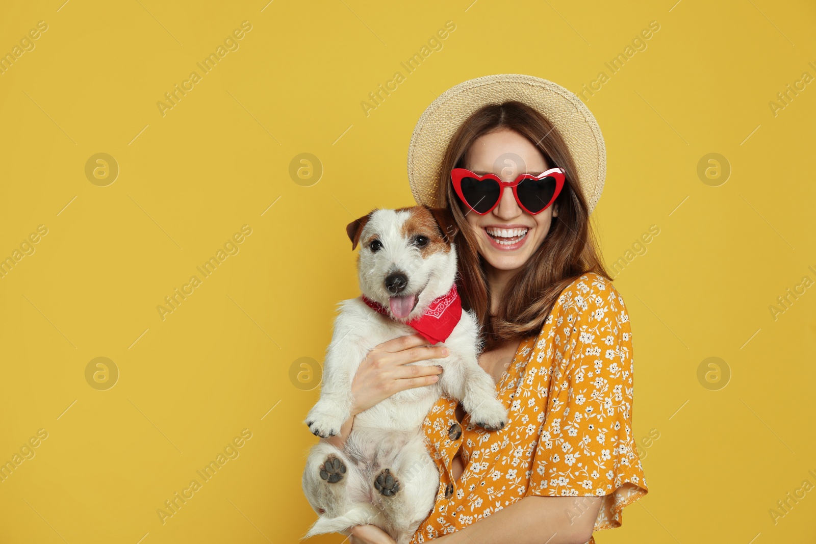 Photo of Young woman with her cute Jack Russell Terrier on yellow background. Lovely pet