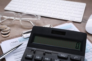 Tax accounting. Calculator, document, pen, coins and keyboard on wooden table, closeup