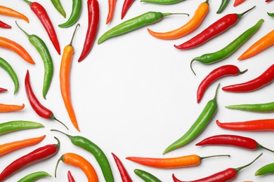 Frame made with different chili peppers on white background, top view. Space for text
