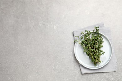 Photo of Bunch of aromatic thyme on light grey table, top view. Space for text