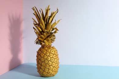 Golden pineapple on color background, space for text. Creative concept