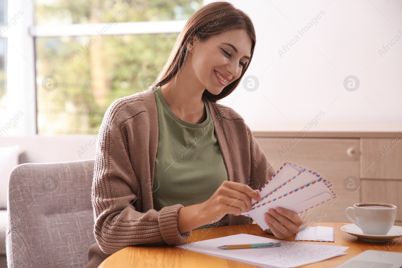 Photo of Woman with letter at wooden table in room