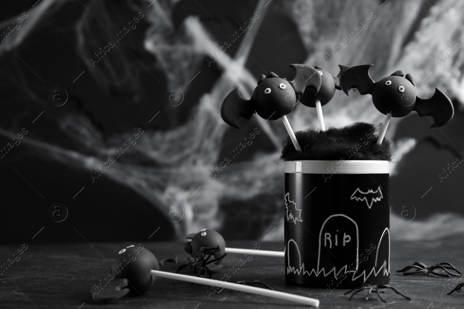 Photo of Bat shaped cake pops on black table, space for text. Halloween treat