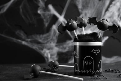 Bat shaped cake pops on black table, space for text. Halloween treat