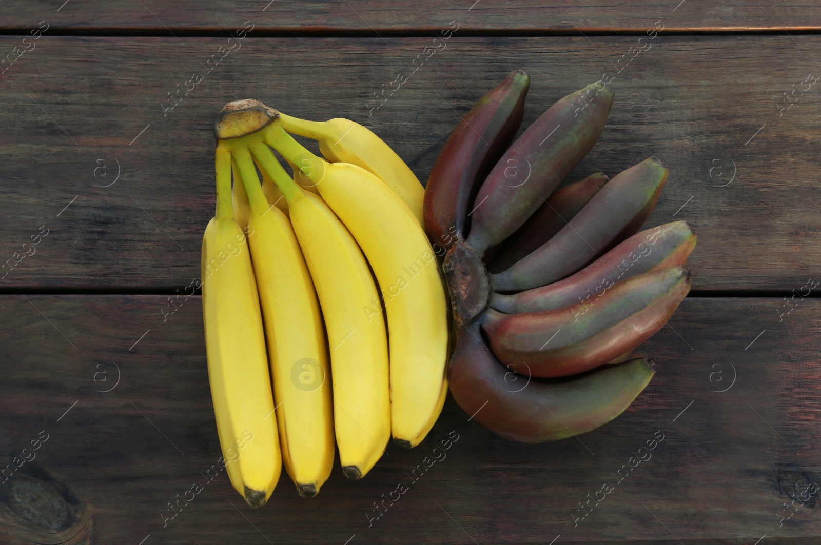 Photo of Tasty purple and yellow bananas on wooden table, flat lay