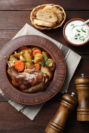 Photo of Tasty cooked rabbit meat with vegetables served on wooden table, flat lay