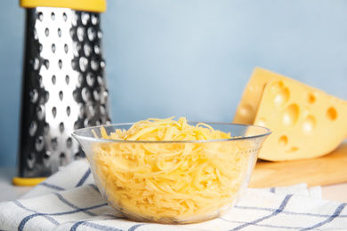 Photo of Delicious grated cheese in glass bowl on table