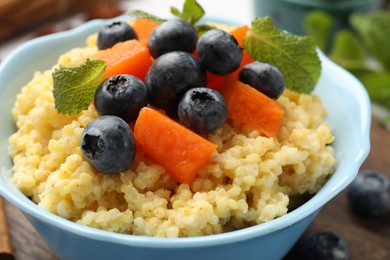 Tasty millet porridge with blueberries, pumpkin and mint in bowl on table, closeup