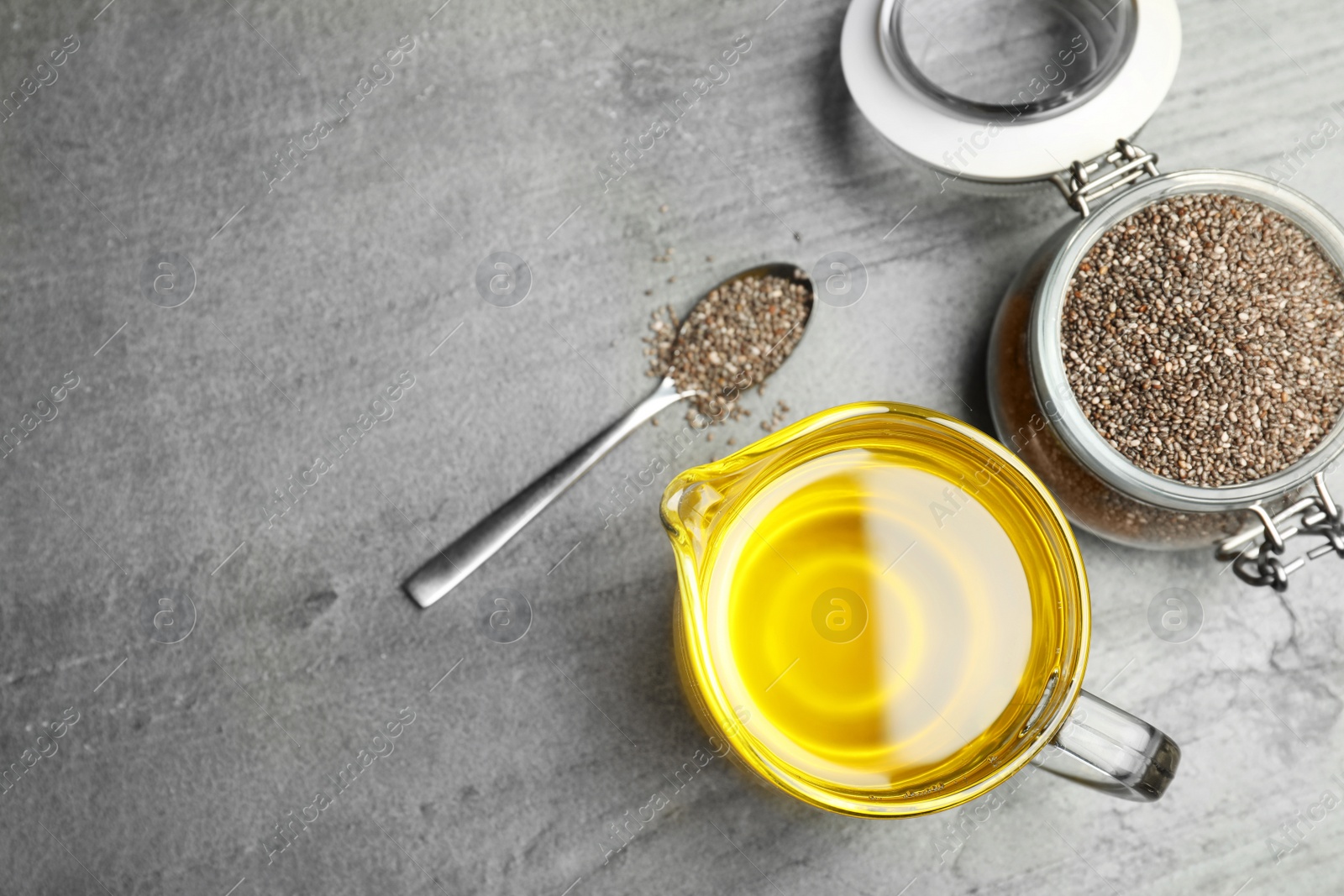 Photo of Flat lay composition with chia oil and seeds on grey background, space for text