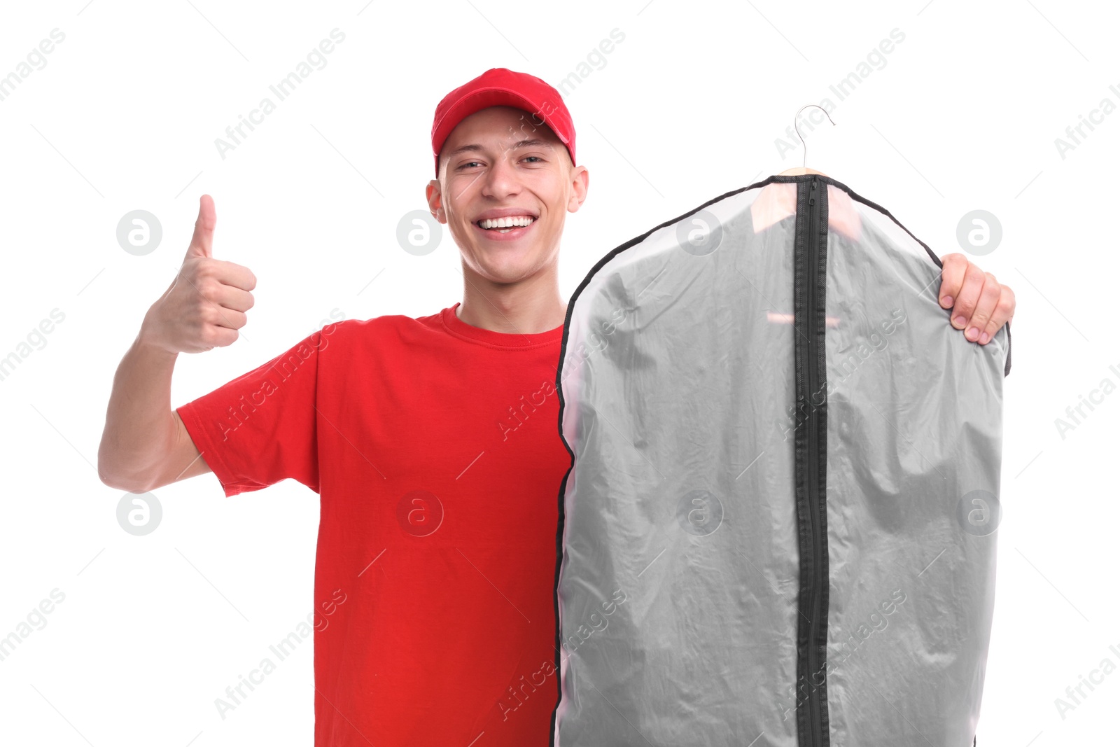 Photo of Dry-cleaning delivery. Happy courier holding garment cover with clothes and showing thumbs up on white background