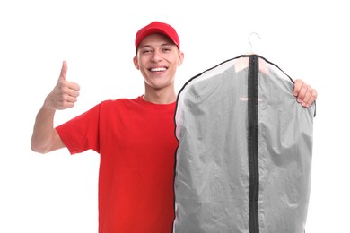 Photo of Dry-cleaning delivery. Happy courier holding garment cover with clothes and showing thumbs up on white background