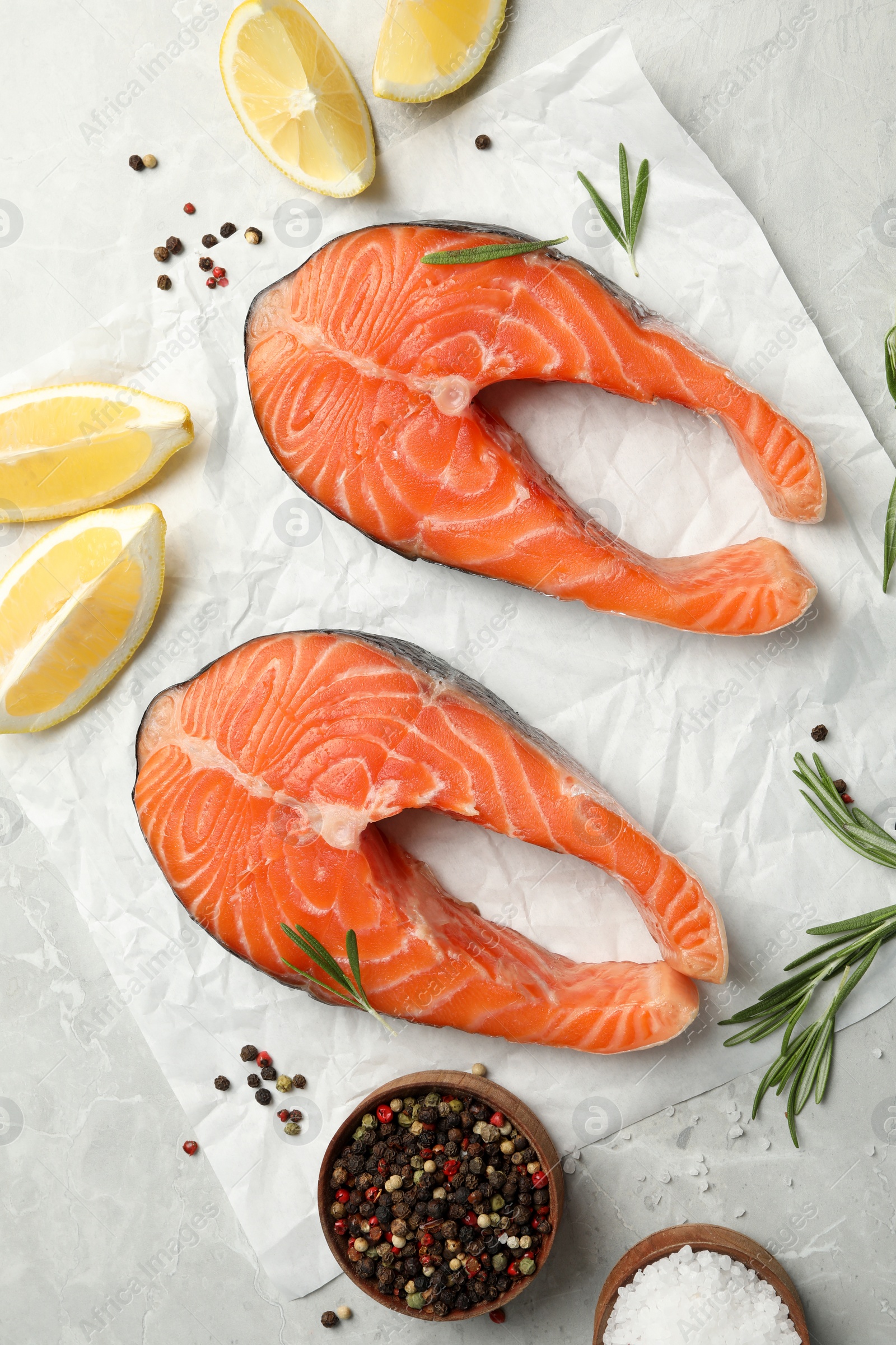 Photo of Fresh salmon steaks with spices, lemon and rosemary on marble table, flat lay