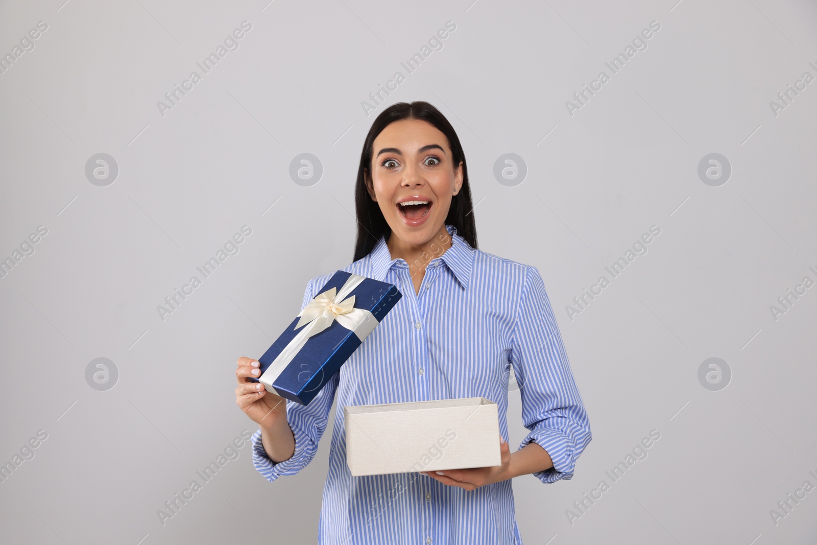 Photo of Emotional young woman opening gift box on light grey background