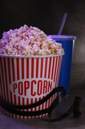 Photo of Delicious popcorn, drink and tape on grey table