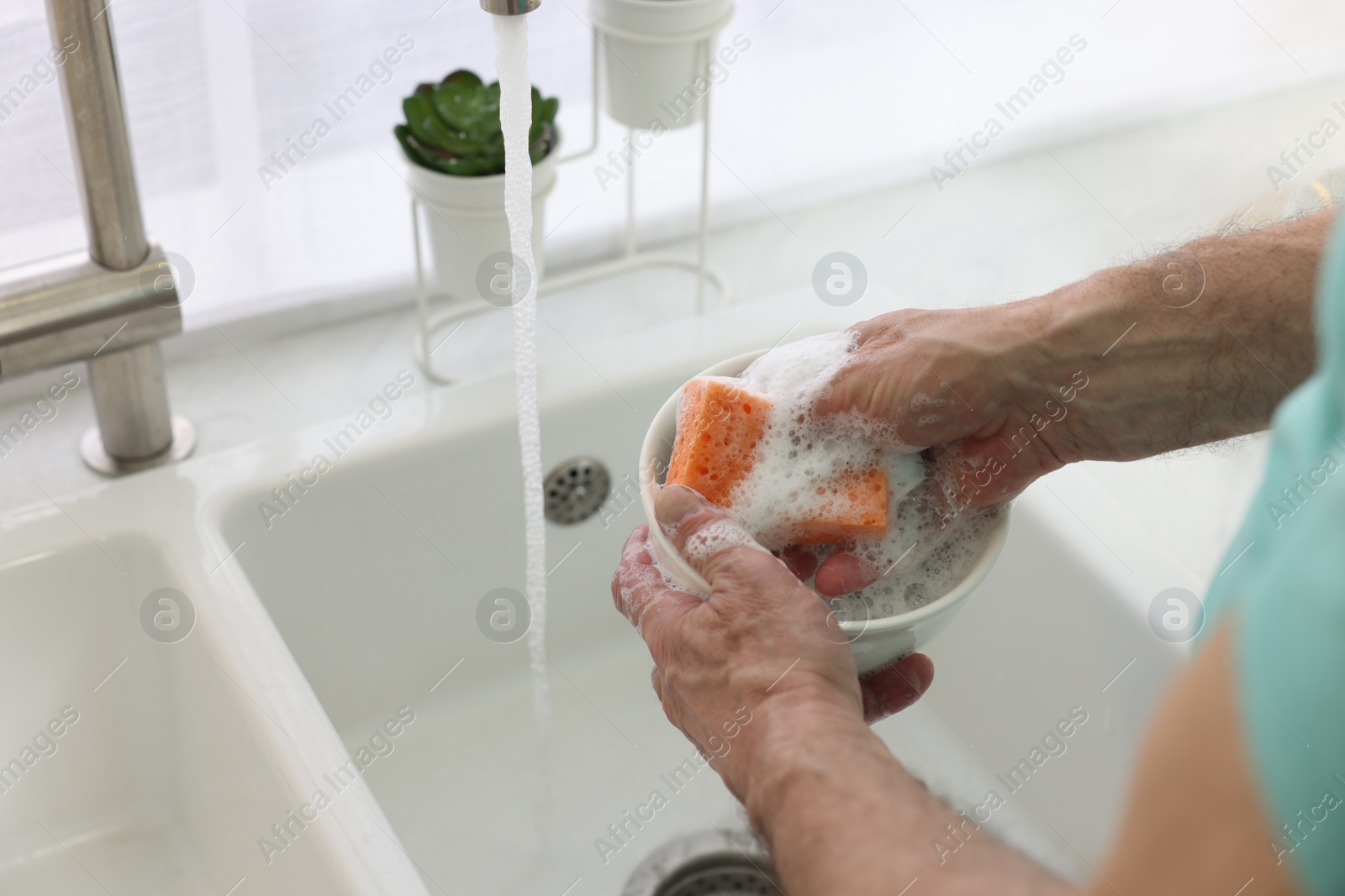 Photo of Man washing bowl above sink in kitchen, closeup