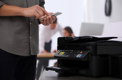 Employee using modern printer in office, closeup