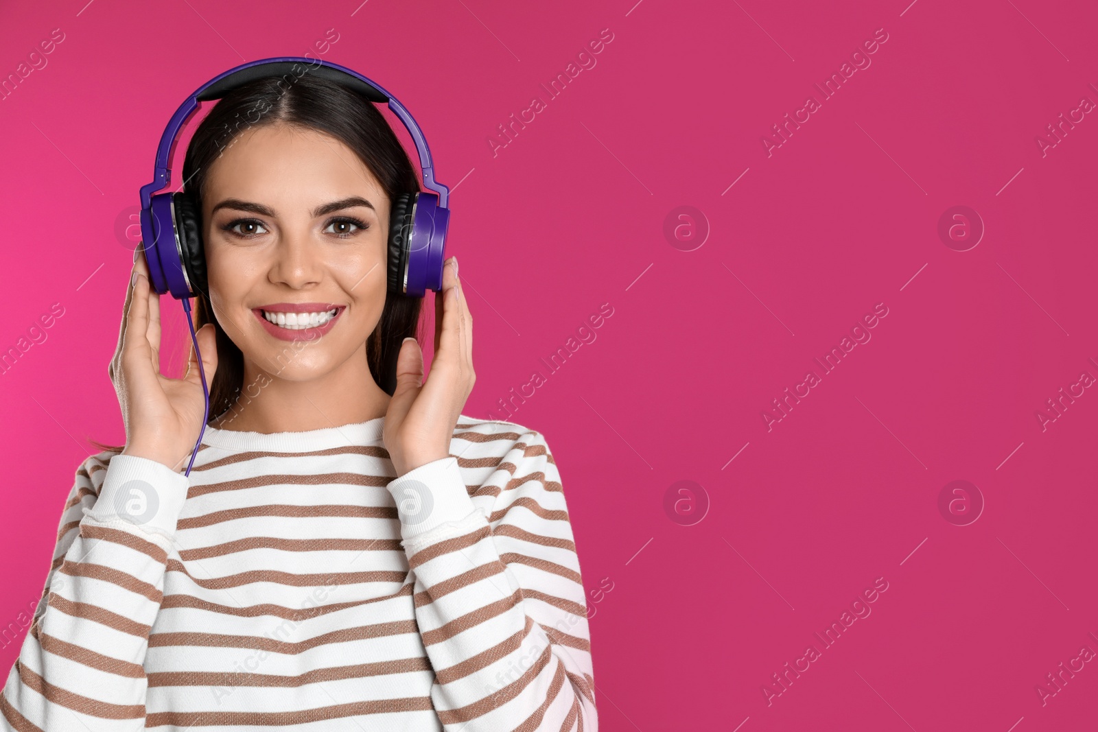 Photo of Attractive young woman enjoying music in headphones on color background. Space for text