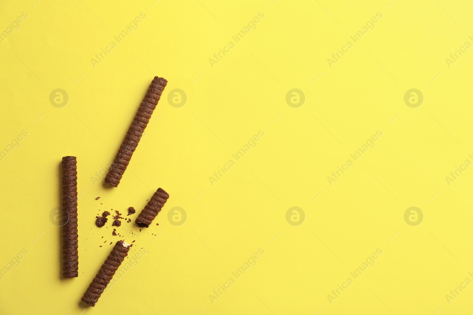 Photo of Tasty wafer rolls on color background, top view. Space for text