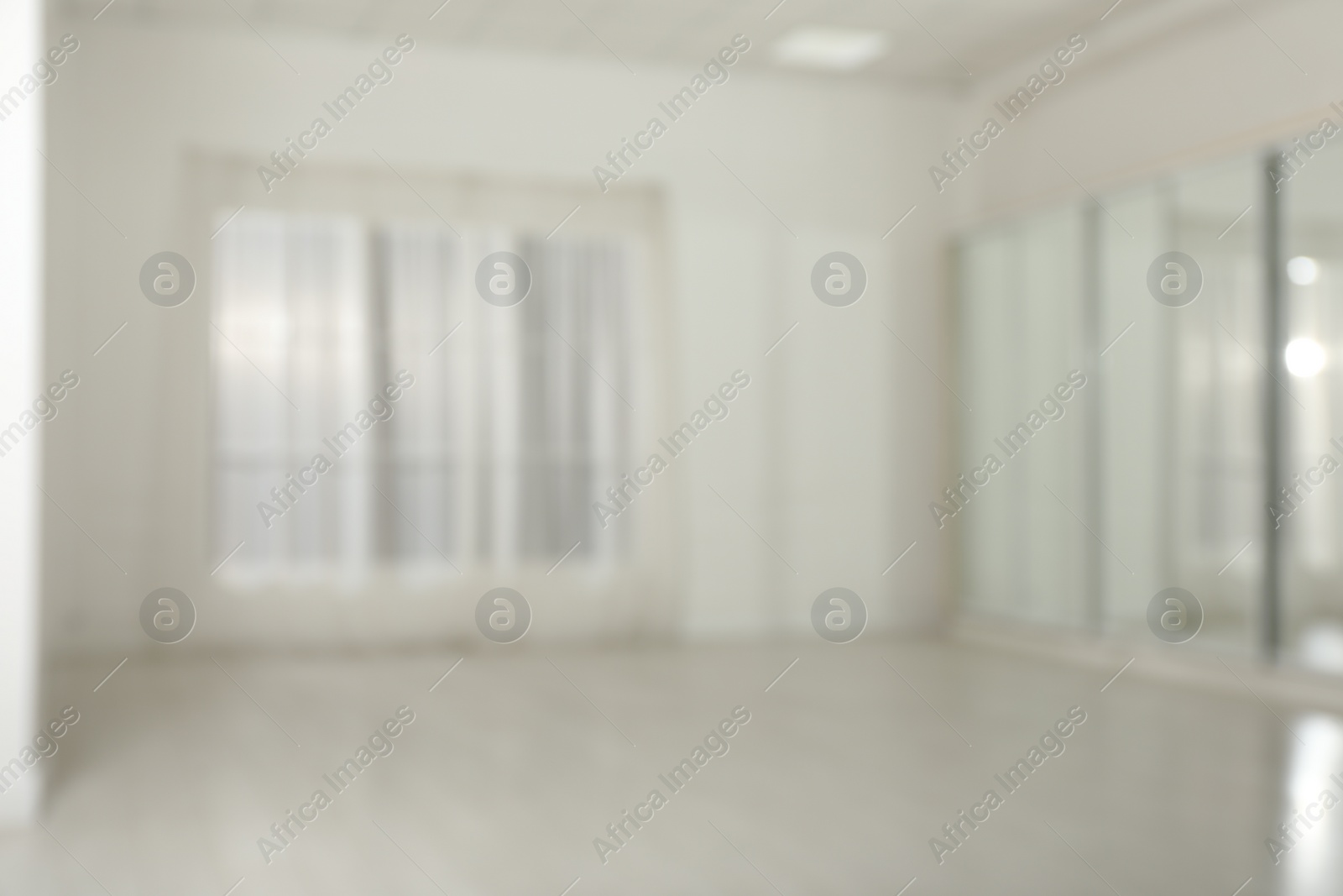 Photo of Empty room with white walls and large window, blurred view