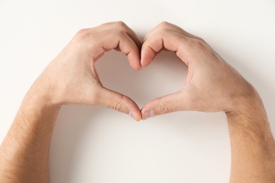 Man making heart with his hands on white background, top view