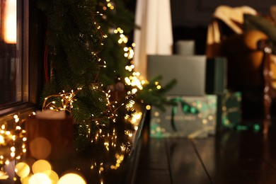 Photo of Fir branches decorated with beautiful Christmas lights in room, space for text