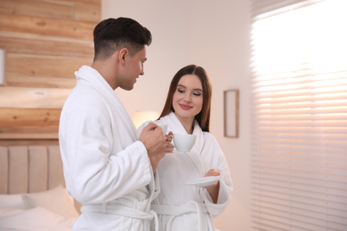 Happy couple in bathrobes with coffee in bedroom