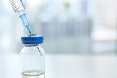 Photo of Vial with vaccine and syringe on blurred background