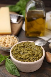 Photo of Tasty pesto sauce and ingredients on wooden table, closeup