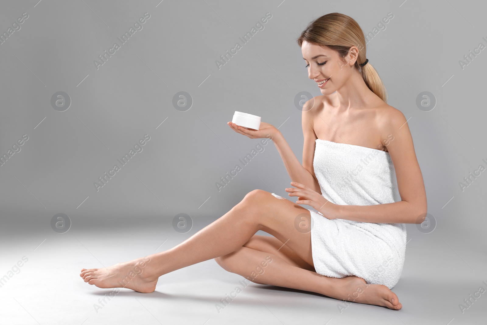 Photo of Young woman with jar of body cream on color background