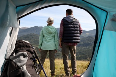Couple in mountains on sunny day, view from camping tent