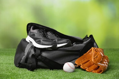 Photo of Bag and different sports equipment on grass against blurred background