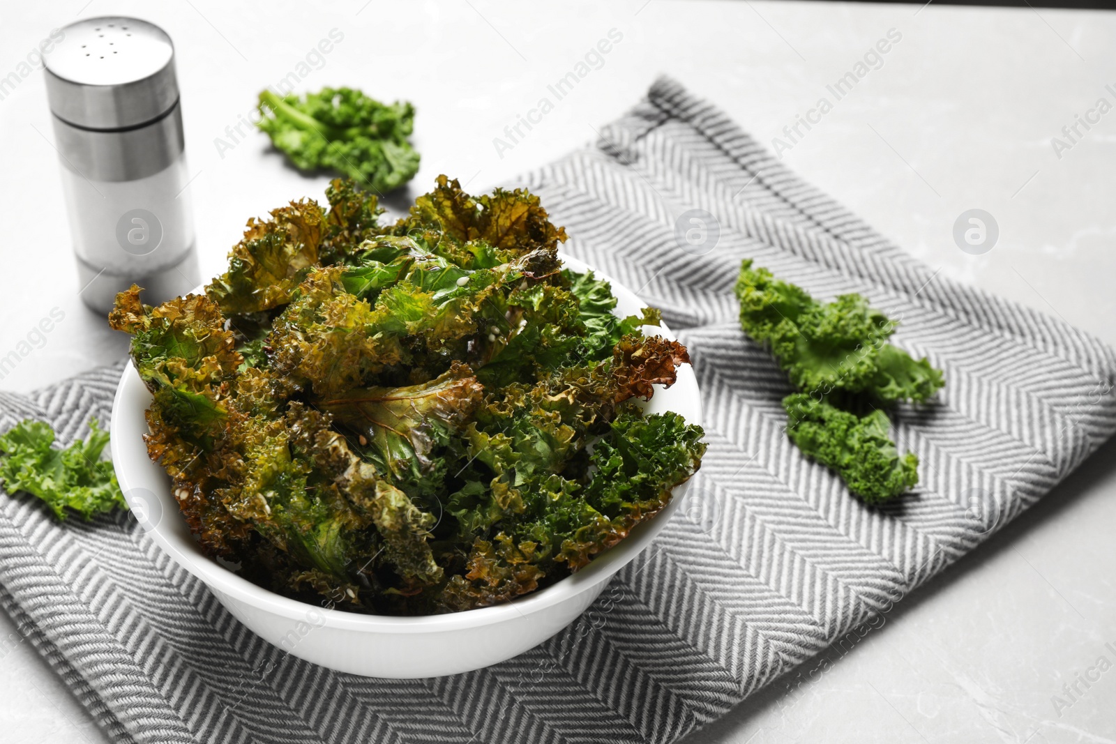 Photo of Tasty baked kale chips on grey marble table