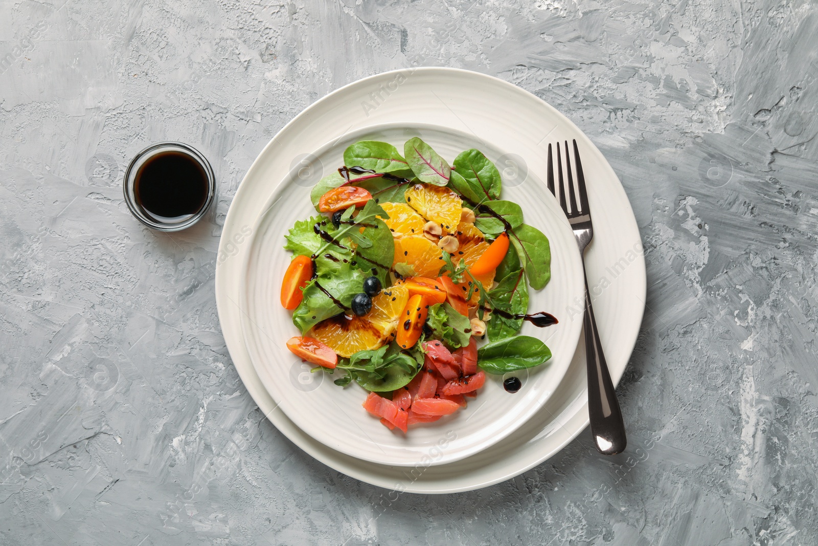 Photo of Delicious salad with salmon served on gray textured table, flat lay