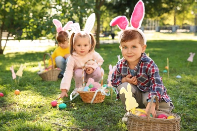 Cute little children hunting eggs in park. Easter tradition