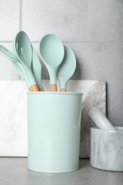 Set of kitchen utensils, mortar with pestle and cutting board on grey table