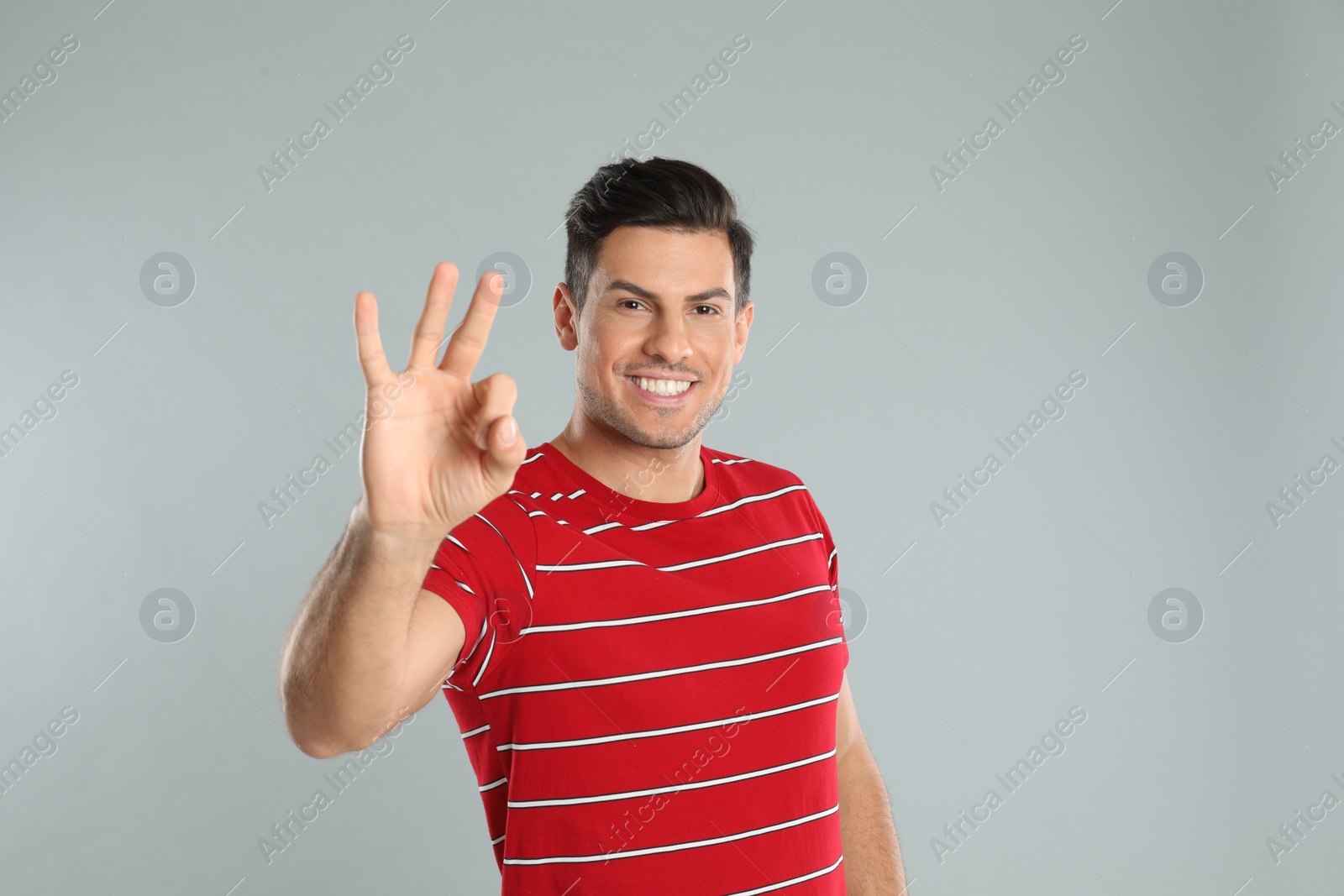 Photo of Man showing number three with his hand on grey background