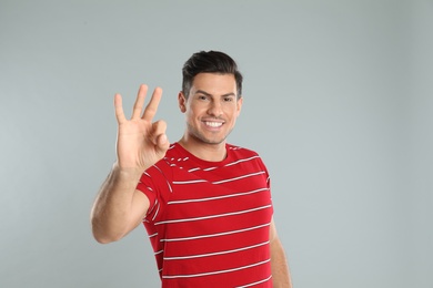 Photo of Man showing number three with his hand on grey background