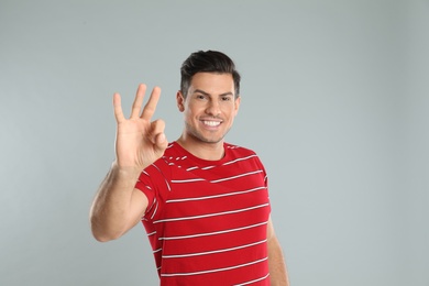 Man showing number three with his hand on grey background