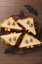 Photo of Tasty monster sandwiches and Halloween decorations on wooden table, flat lay
