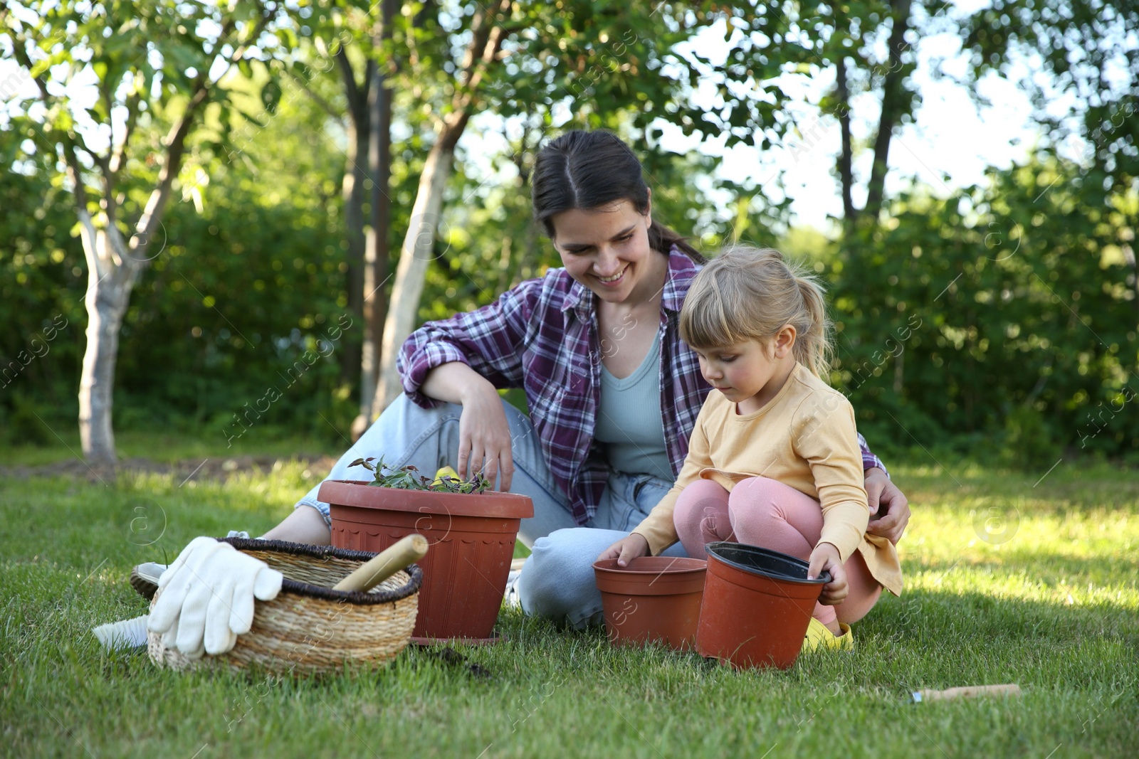 Photo of Mother and her daughter planting tree together in garden