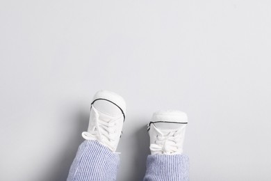 Photo of Little baby in stylish gumshoes on light grey background, top view. Space for text