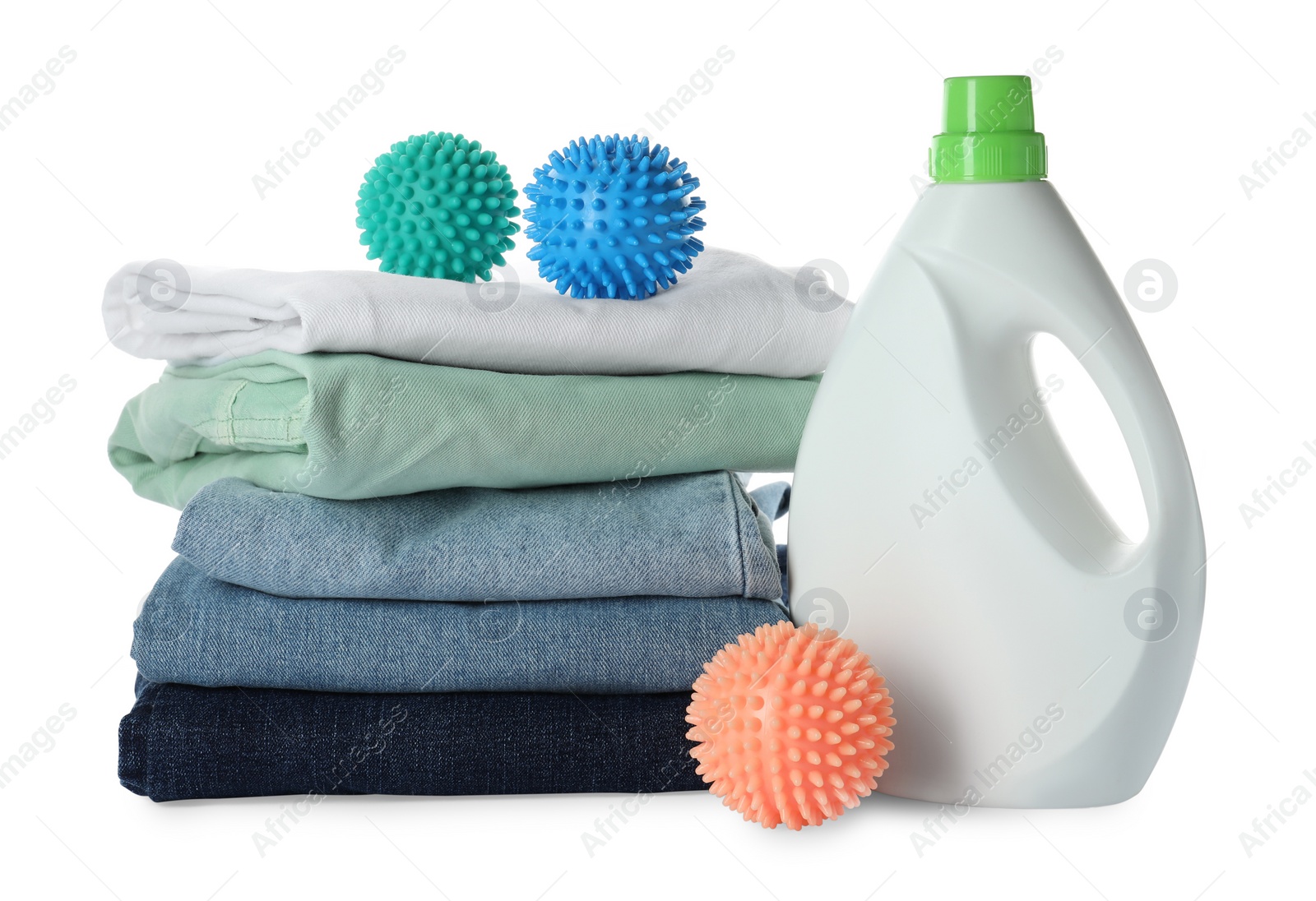 Photo of Color dryer balls, laundry detergent and stacked clean clothes on white background