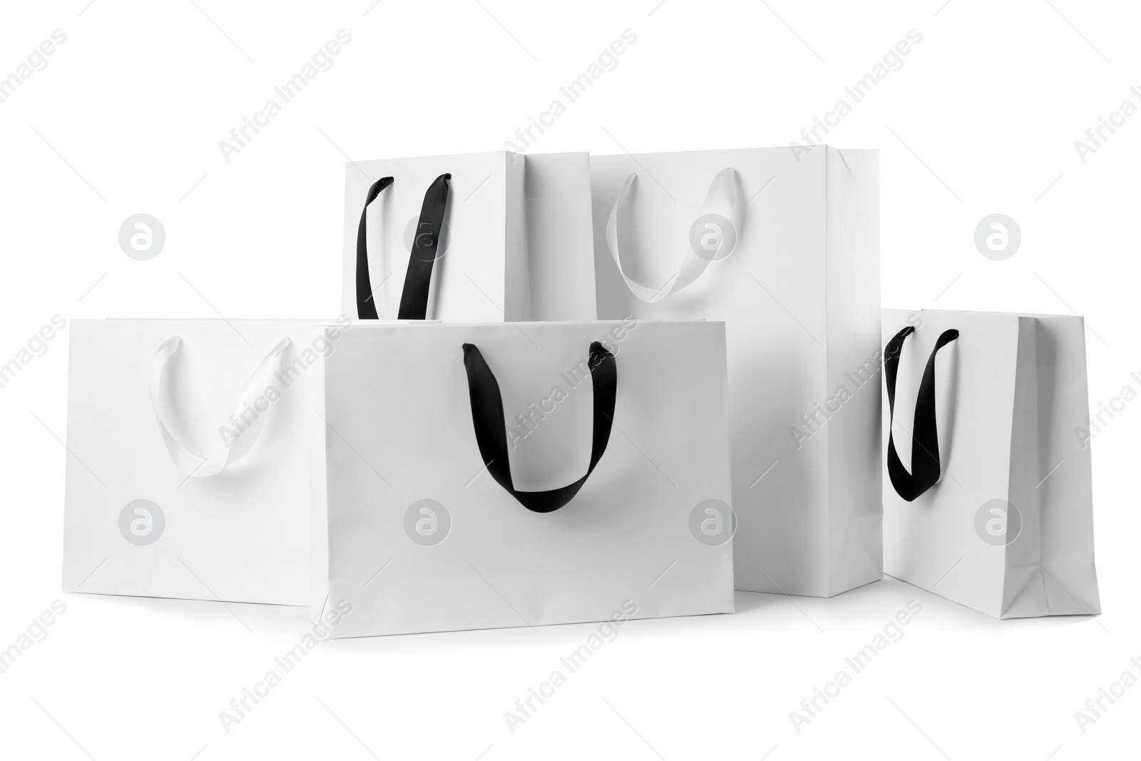 Photo of Paper shopping bags with ribbon handles on white background. Mockup for design