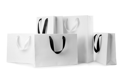 Photo of Paper shopping bags with ribbon handles on white background. Mockup for design